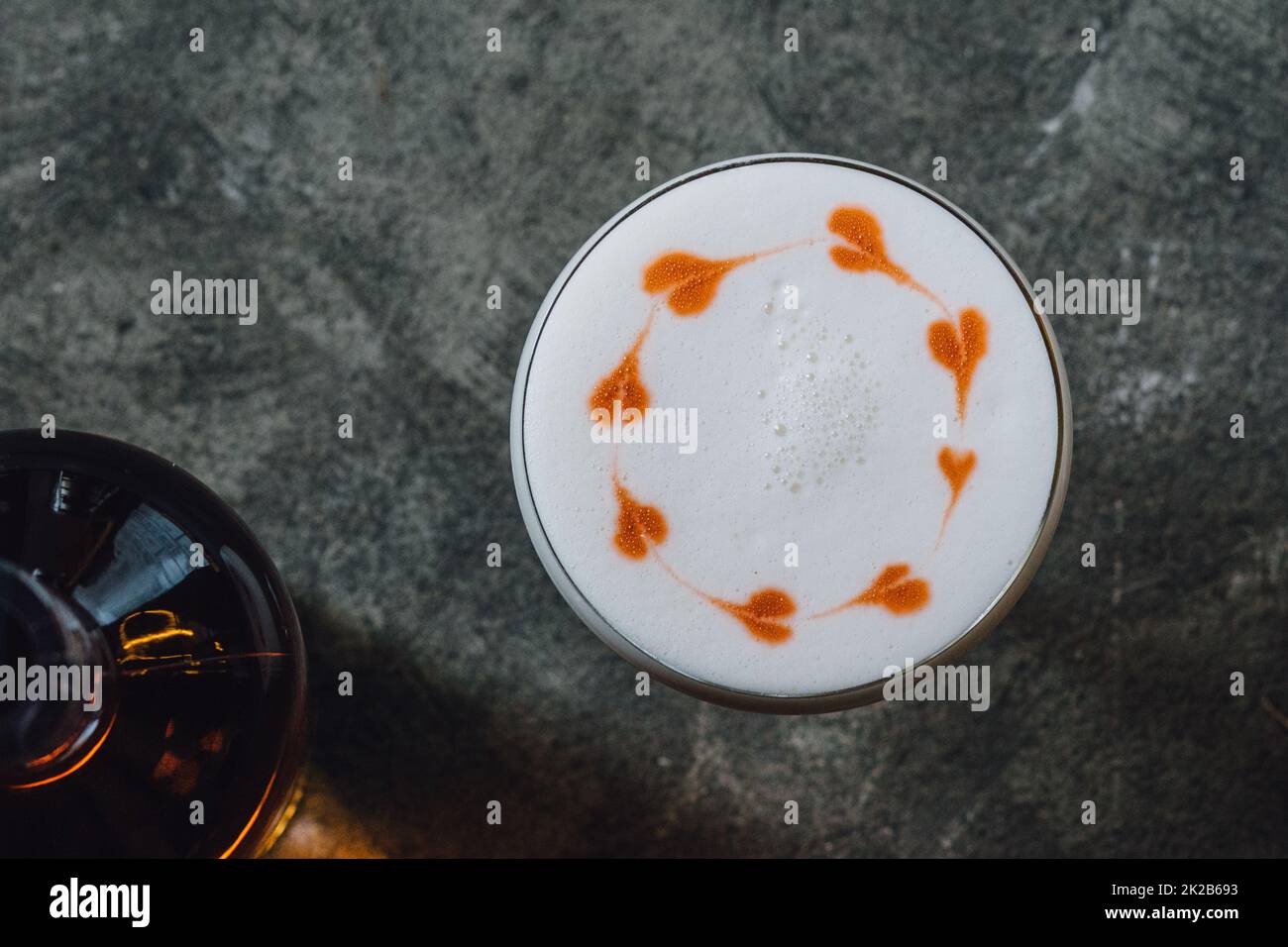 Whiskey Sour with foam froth with heart designs on concrete background