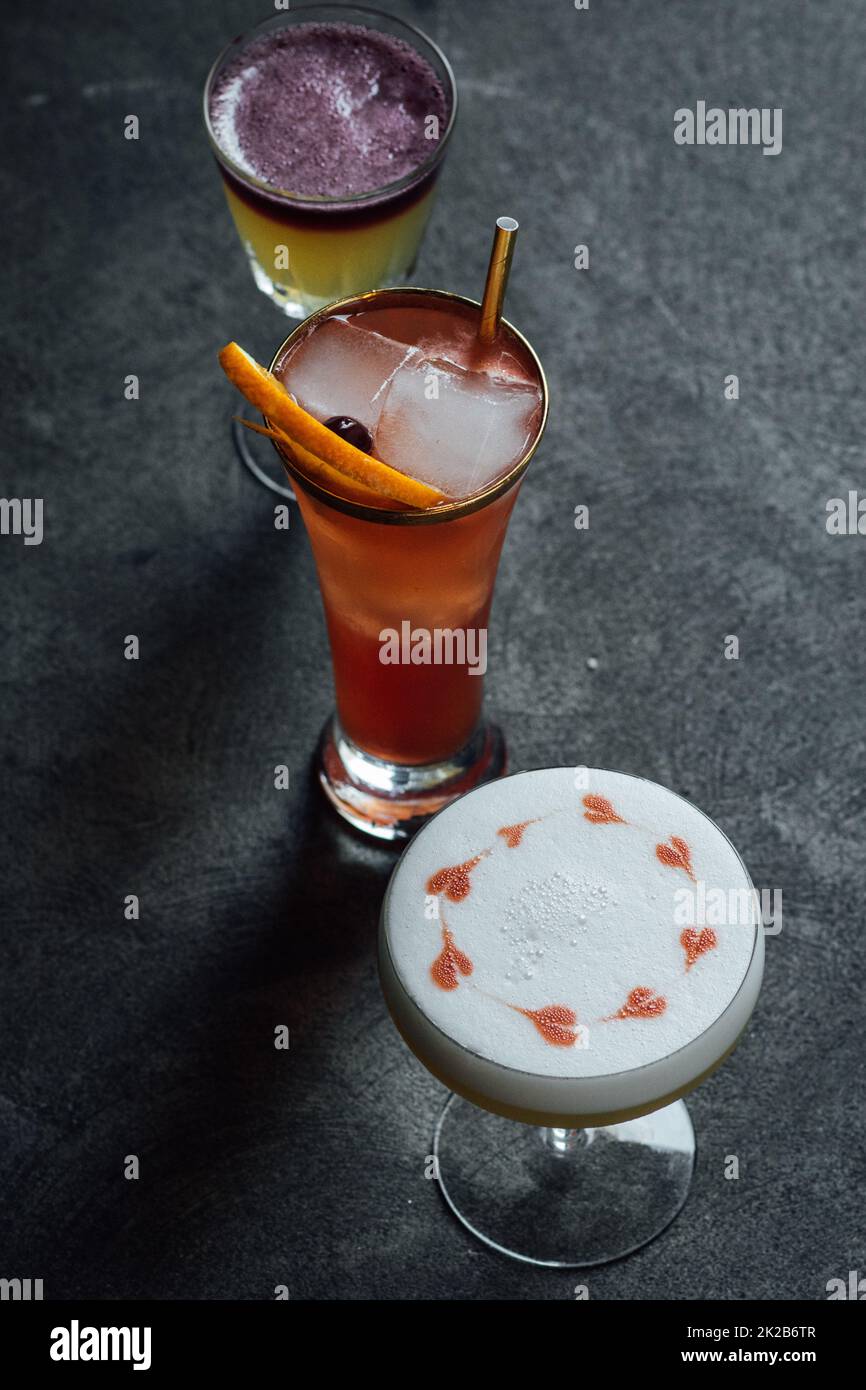 collection of three cocktails, whiskey sours, hearts drawn with bitters