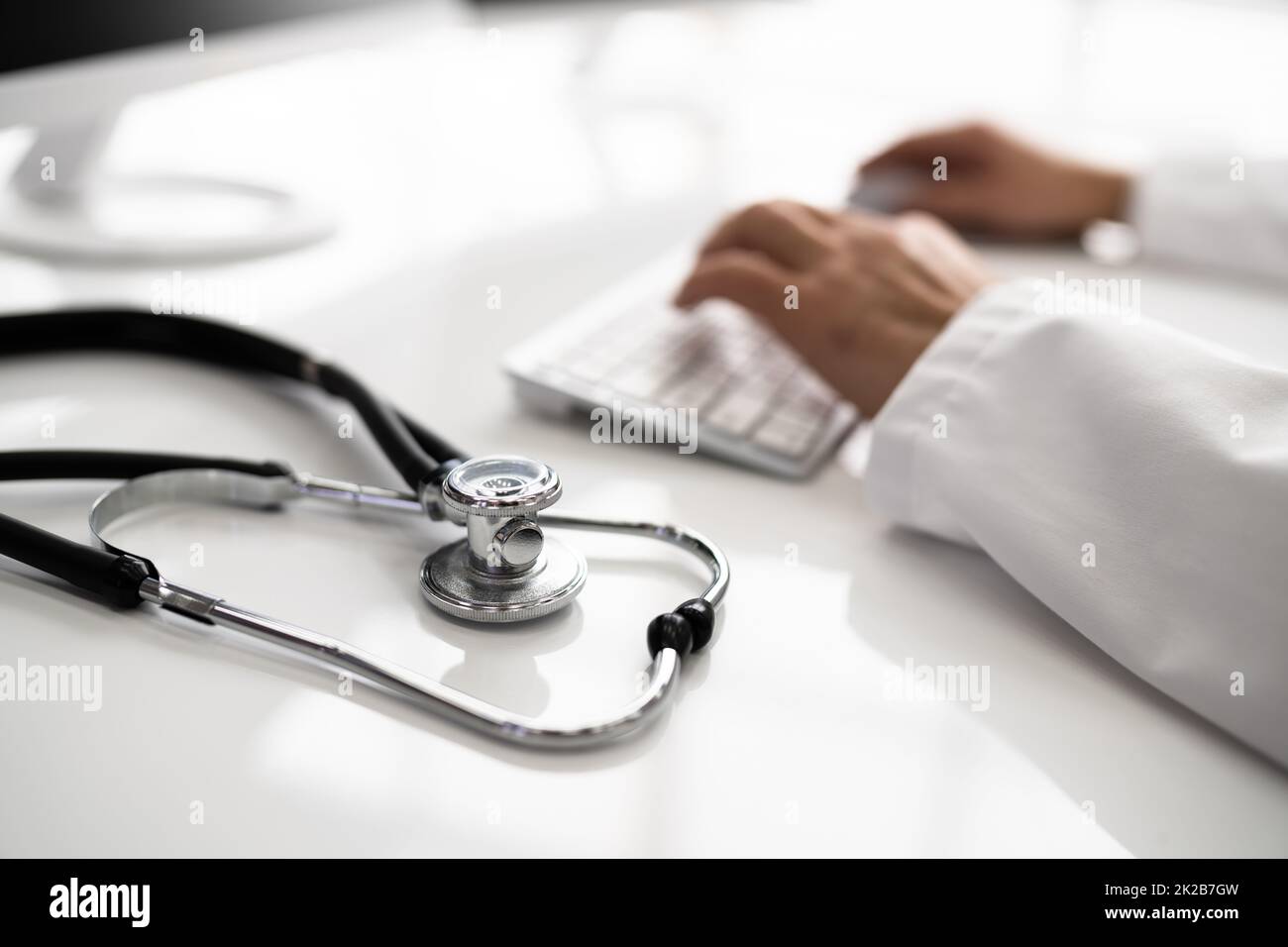 View Of Stethoscope With Doctor Using Computer Keyboard Stock Photo