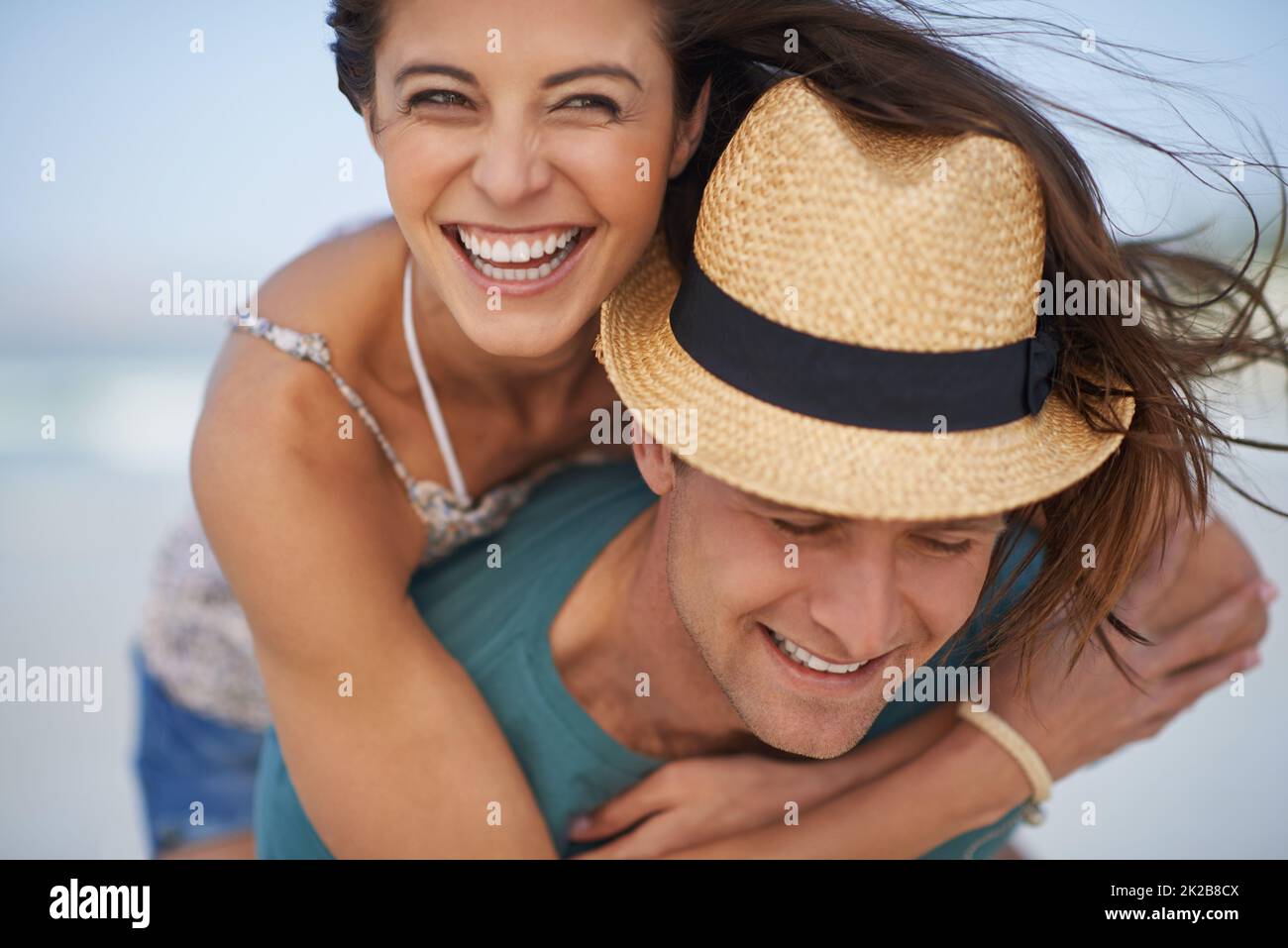 They always have fun together. A young couple piggybacking at the beach. Stock Photo