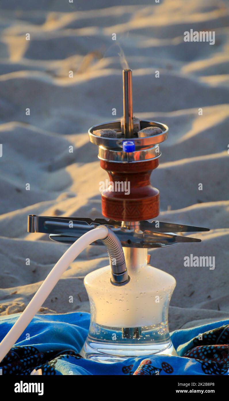A hookah or shisha stands on a towel on the beach Stock Photo Alamy