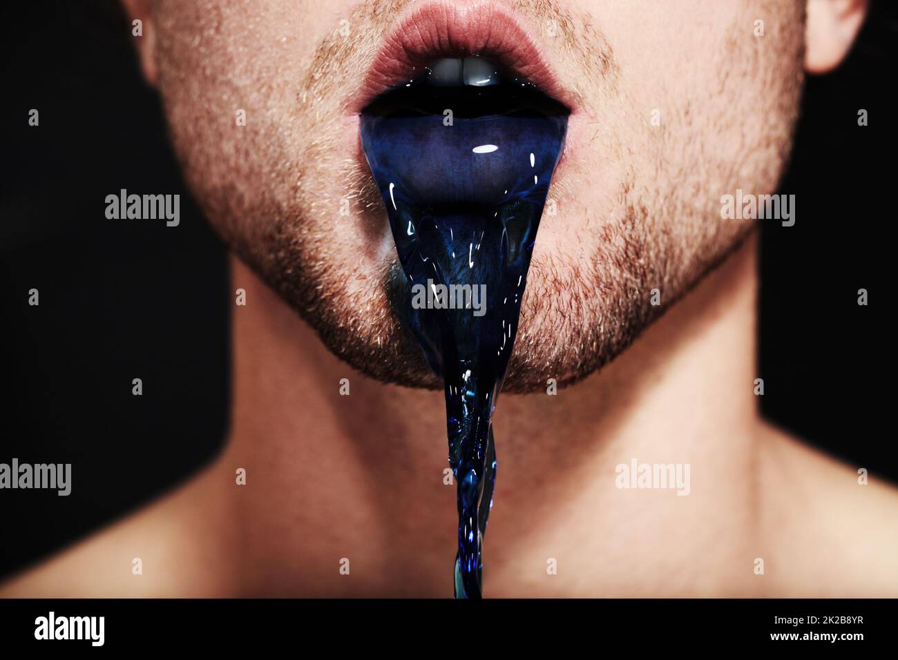 The colour of lies. Closeup of a young mans mouth spitting out purple liquid. Stock Photo