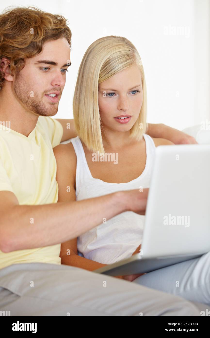 Checking on holiday destinations. A happy young couple looking at holiday destinations on their laptop. Stock Photo