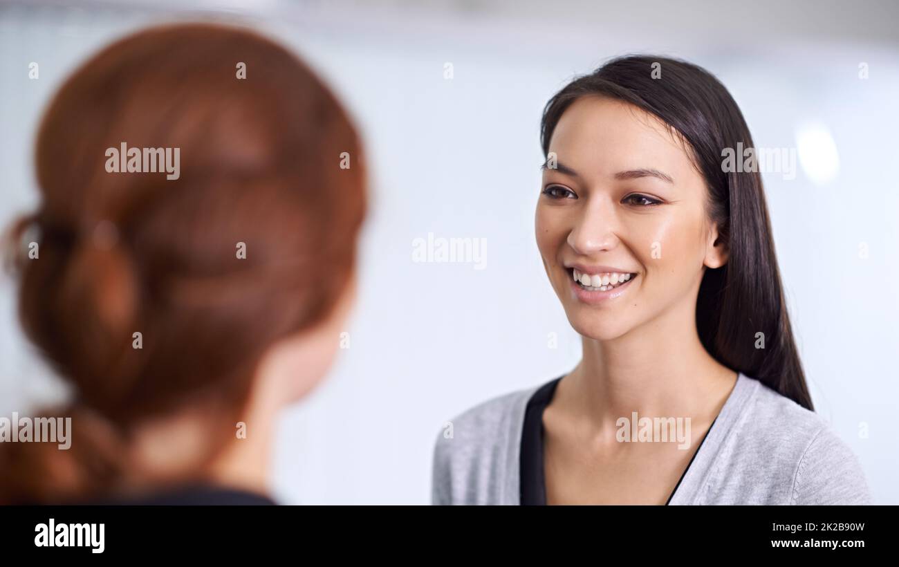 Gossip girls. A cropped shot of two young professionals talking in the office. Stock Photo