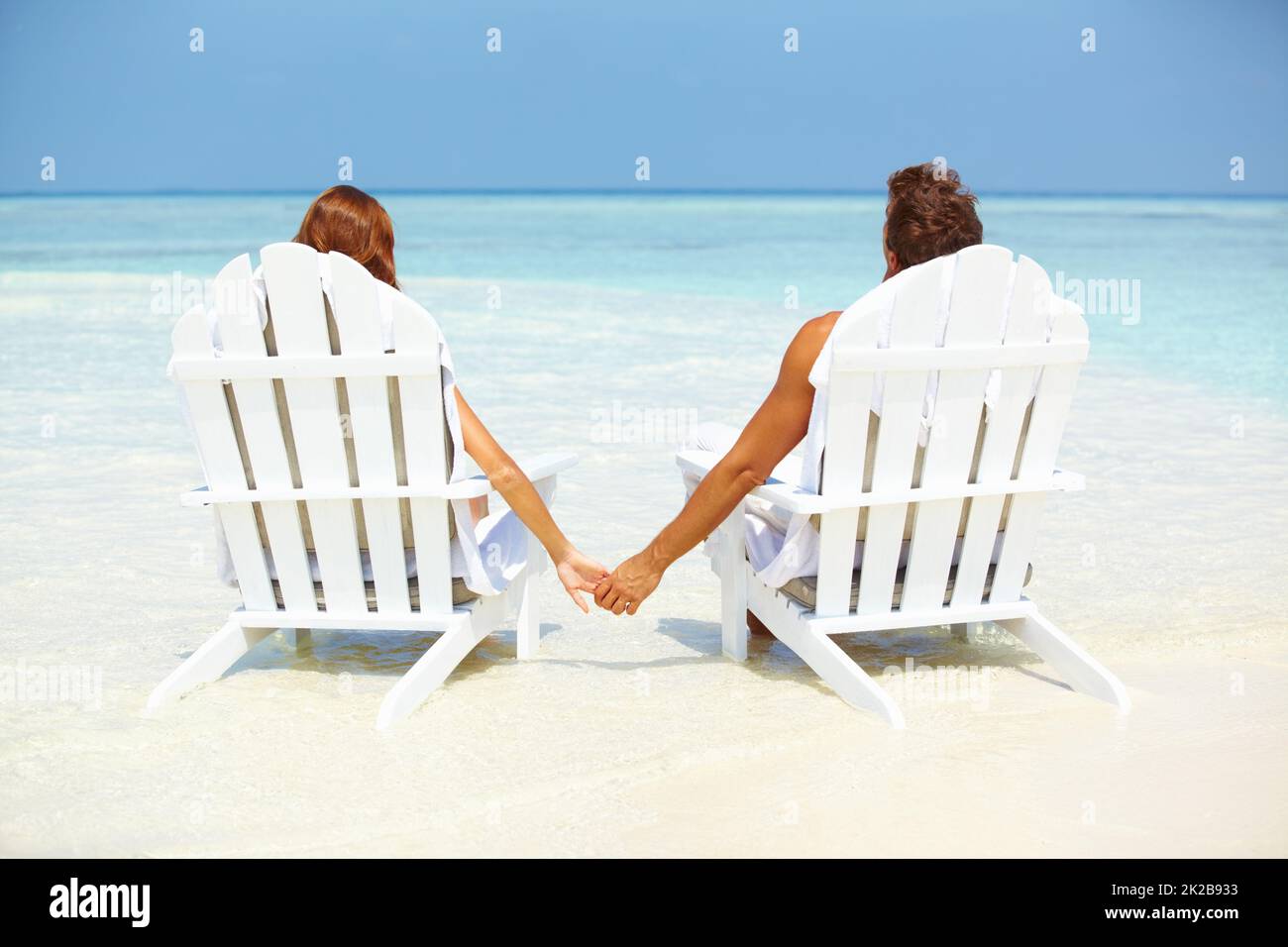 Loving couple relaxing on deck chairs. Rear view of loving couple