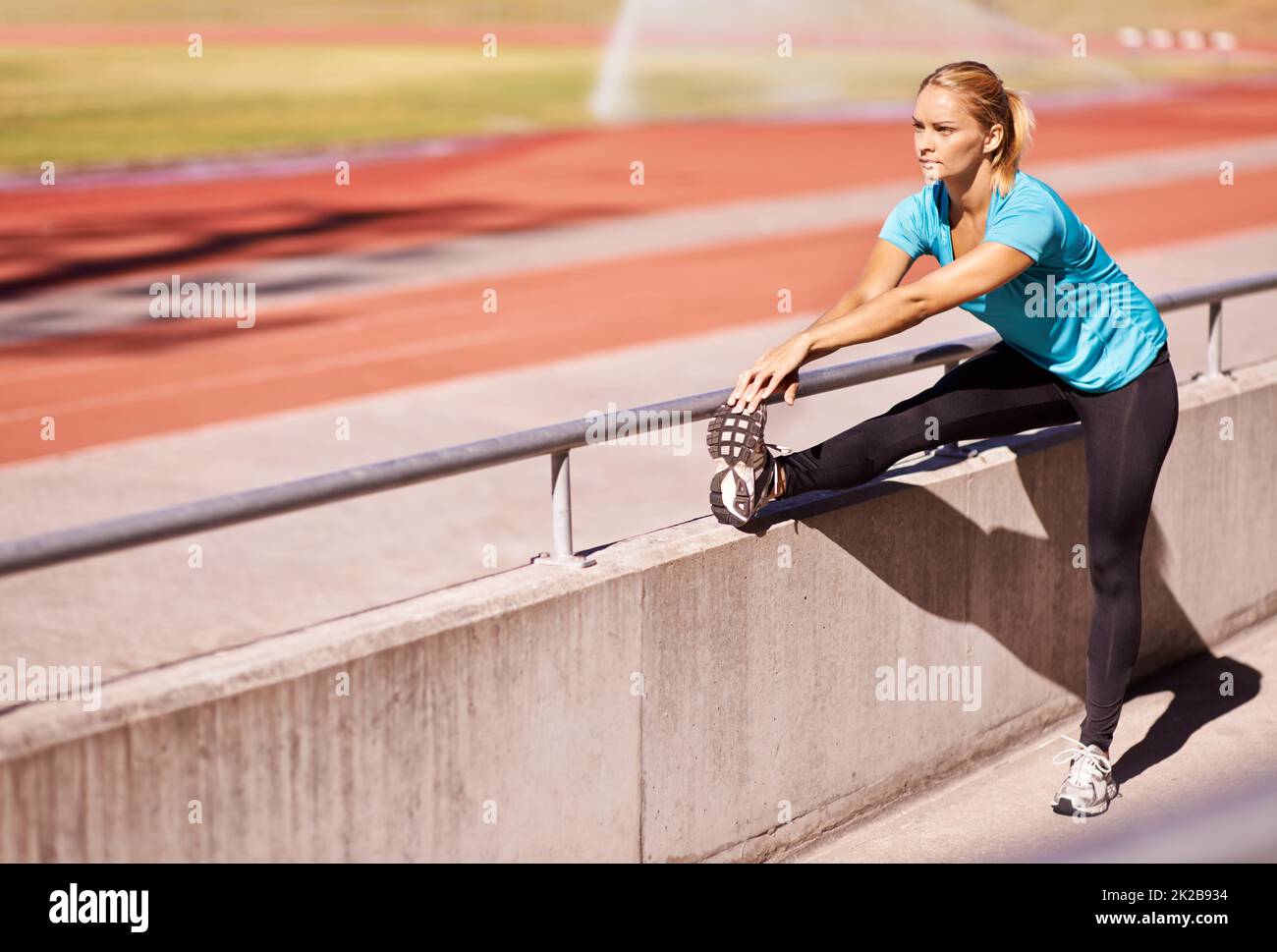 Ready for a race. Shot of an attractive young runner stretching out on the track. Stock Photo