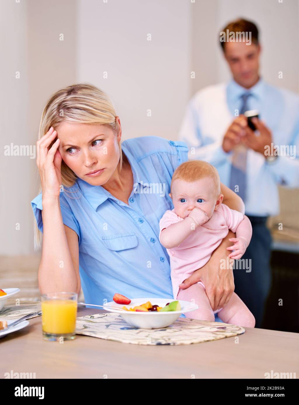 I didnt sleep well last night. Young mother looking stressed while husband gets ready for work. Stock Photo