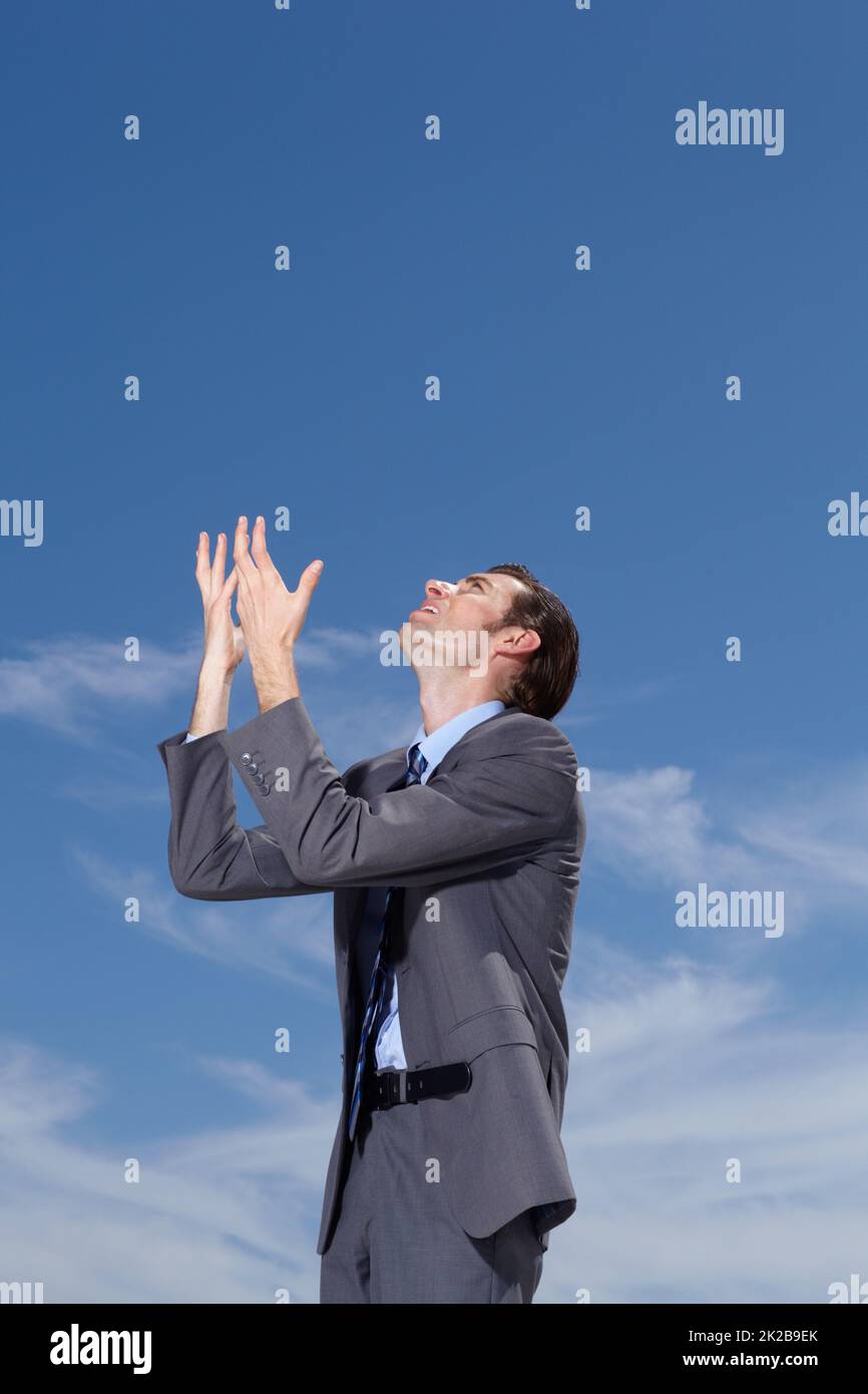 Tell me why. A young businessman pleading to the sky for answers. Stock Photo