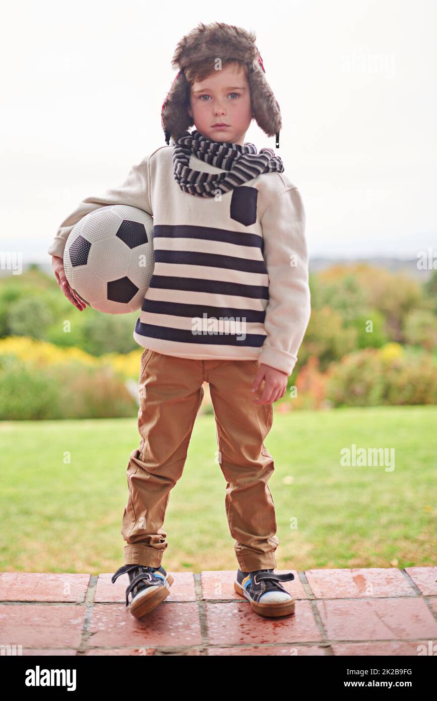Rain or shine. Shot of a little boy standing outside with his soccer ball. Stock Photo