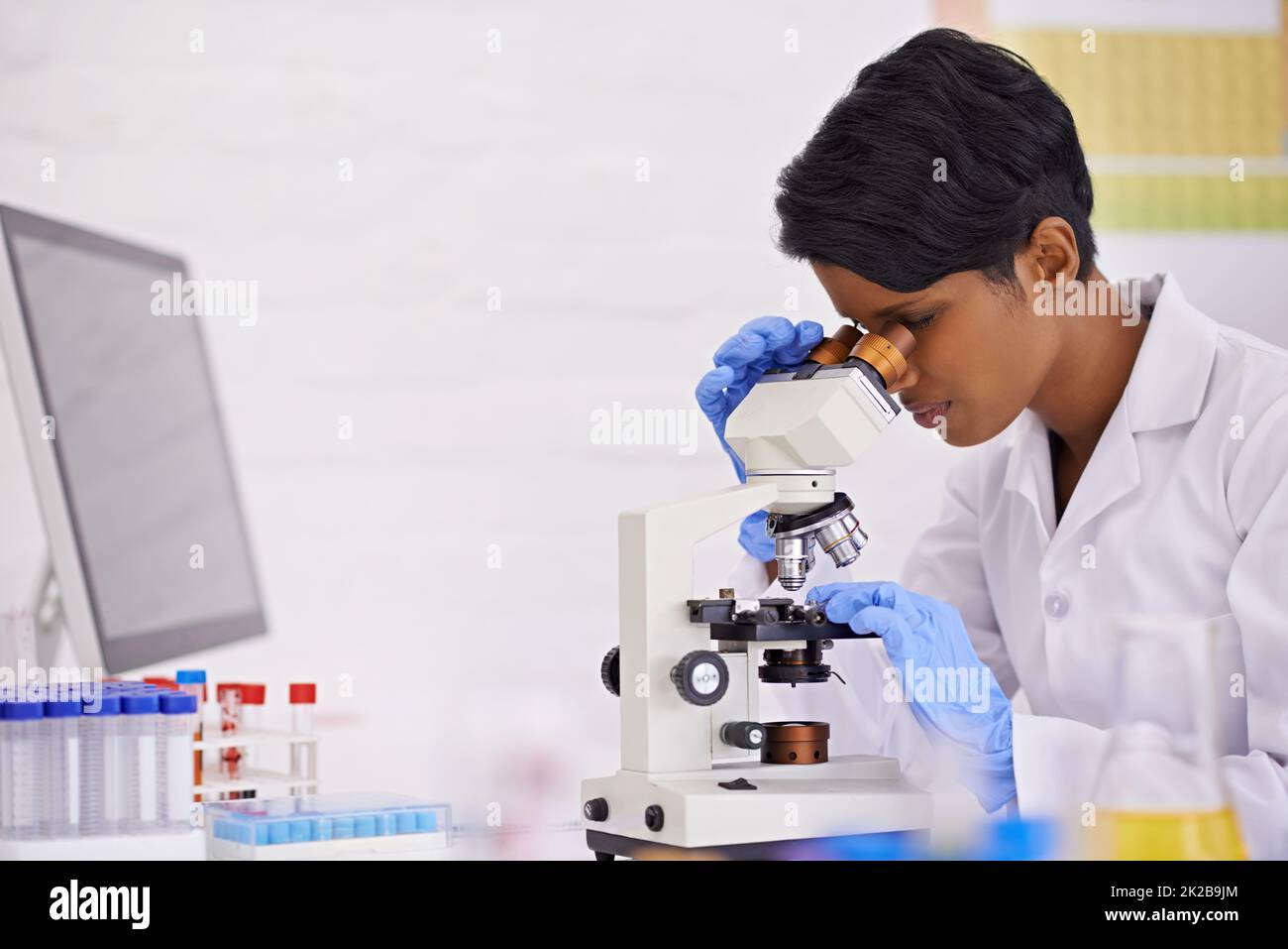 A perfectionist at work. A young scientist using a microscope at her desk in her lab. Stock Photo