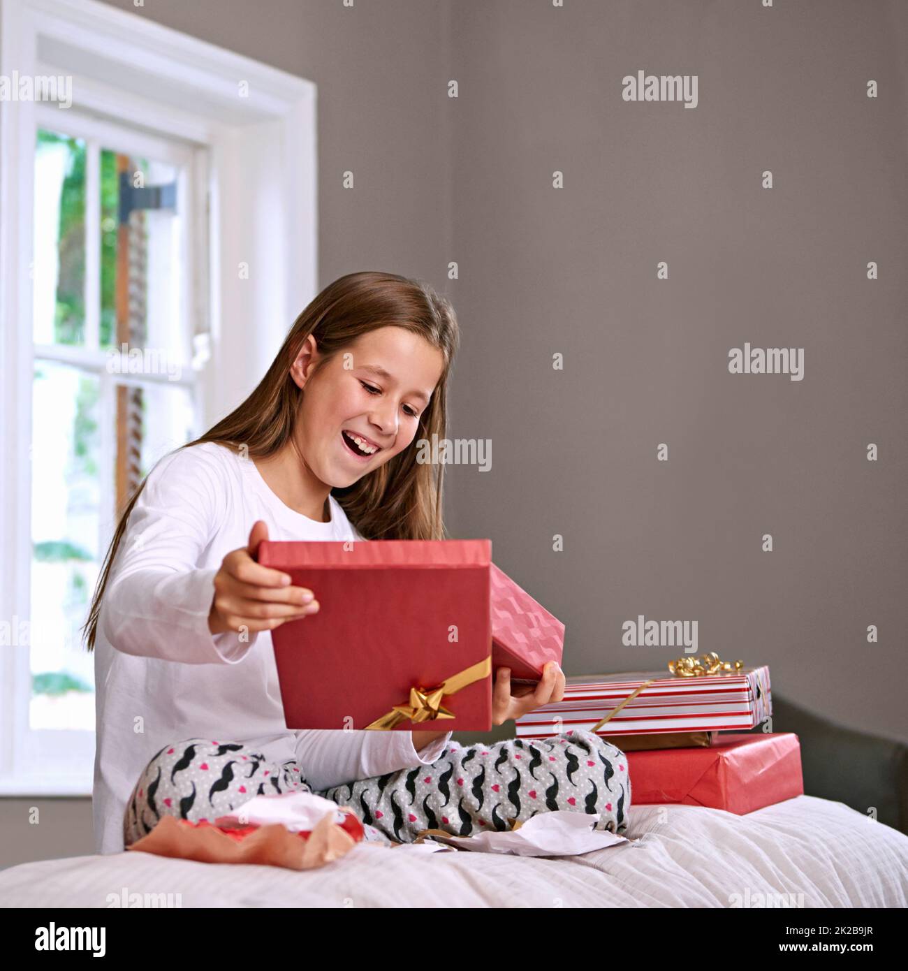 Its just what I wanted. Shot of an excited young girl opening her birthday gifts. Stock Photo