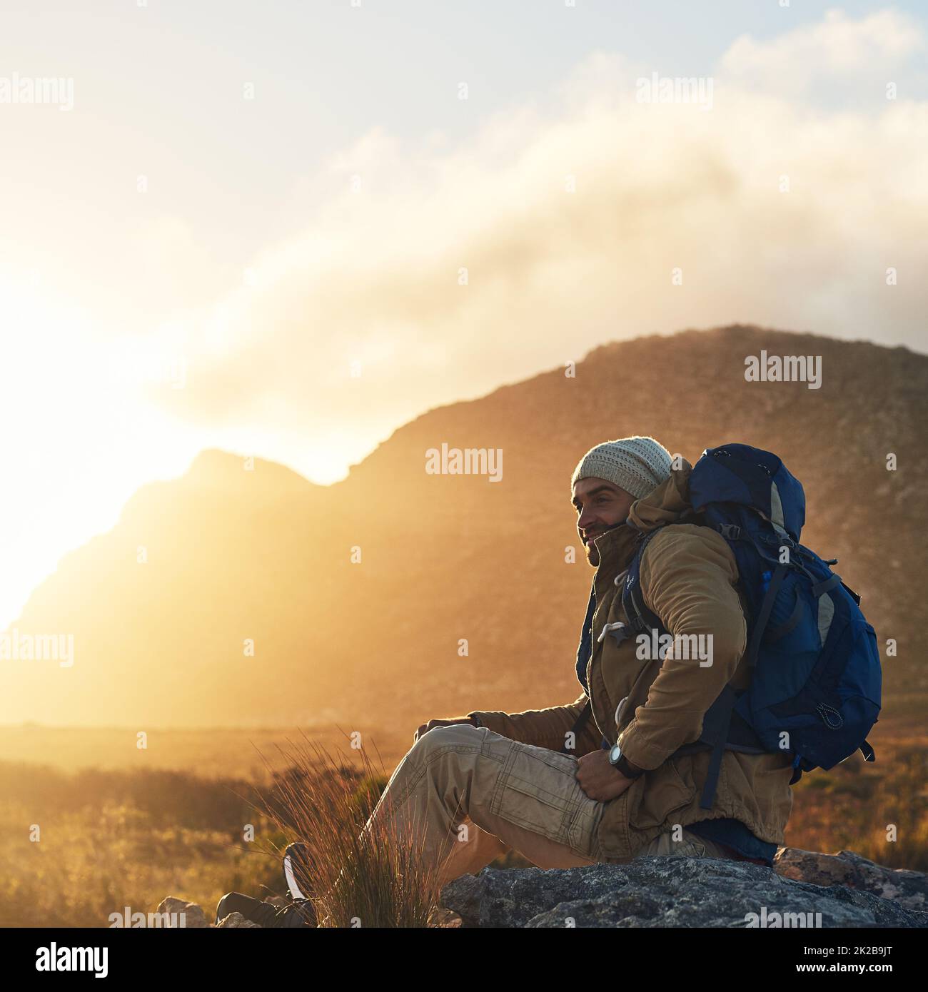 Embrace yourself and you embrace the world. Shot of a hiker sitting on top of a mountain smiling. Stock Photo
