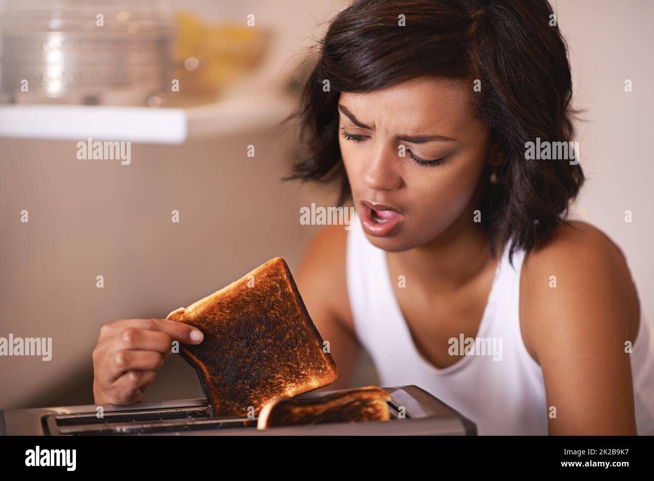 Oh no. Cropped shot of a young woman taking a piece of burnt toast from the toaster Stock Photo
