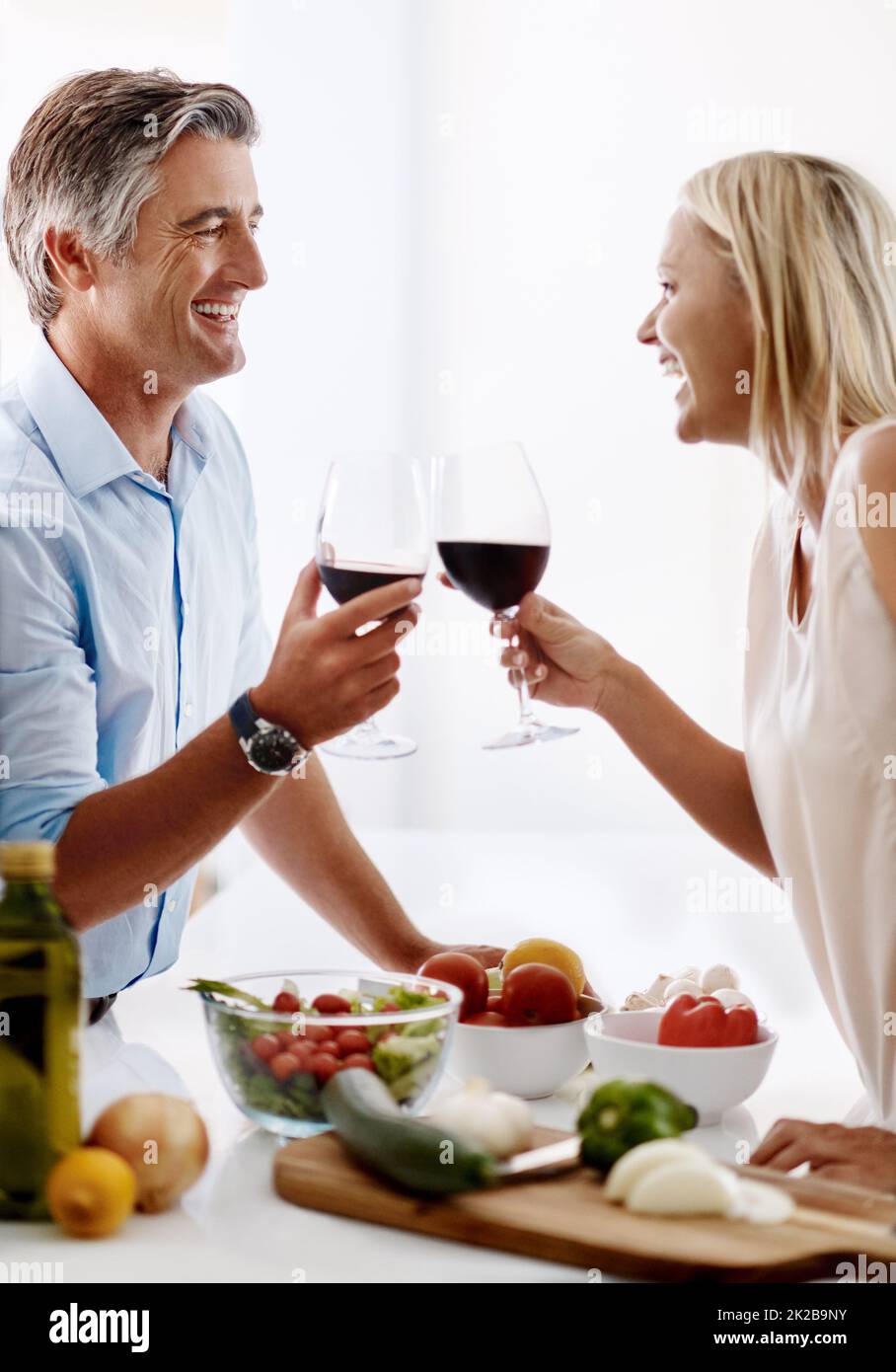 Lets toast to cooking. Cropped shot of an affectionate mature couple toasting with red wine while making dinner. Stock Photo