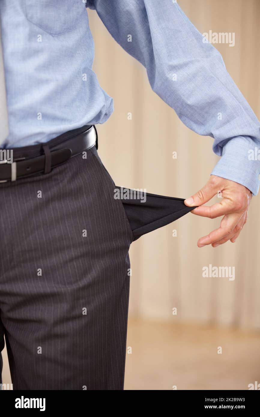 Underpaid. A cropped image of a businessman turning out his pocket and showing that it is empty. Stock Photo