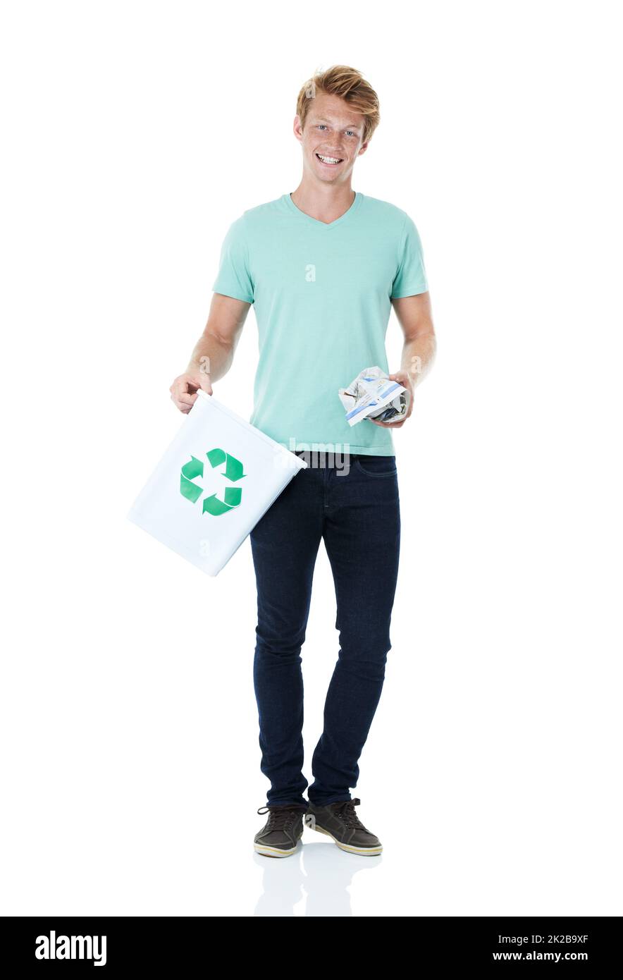 Getting in the right habit. A handsome young red-headed man ready to throw away a piece of paper in the recycling bin - portrait. Stock Photo