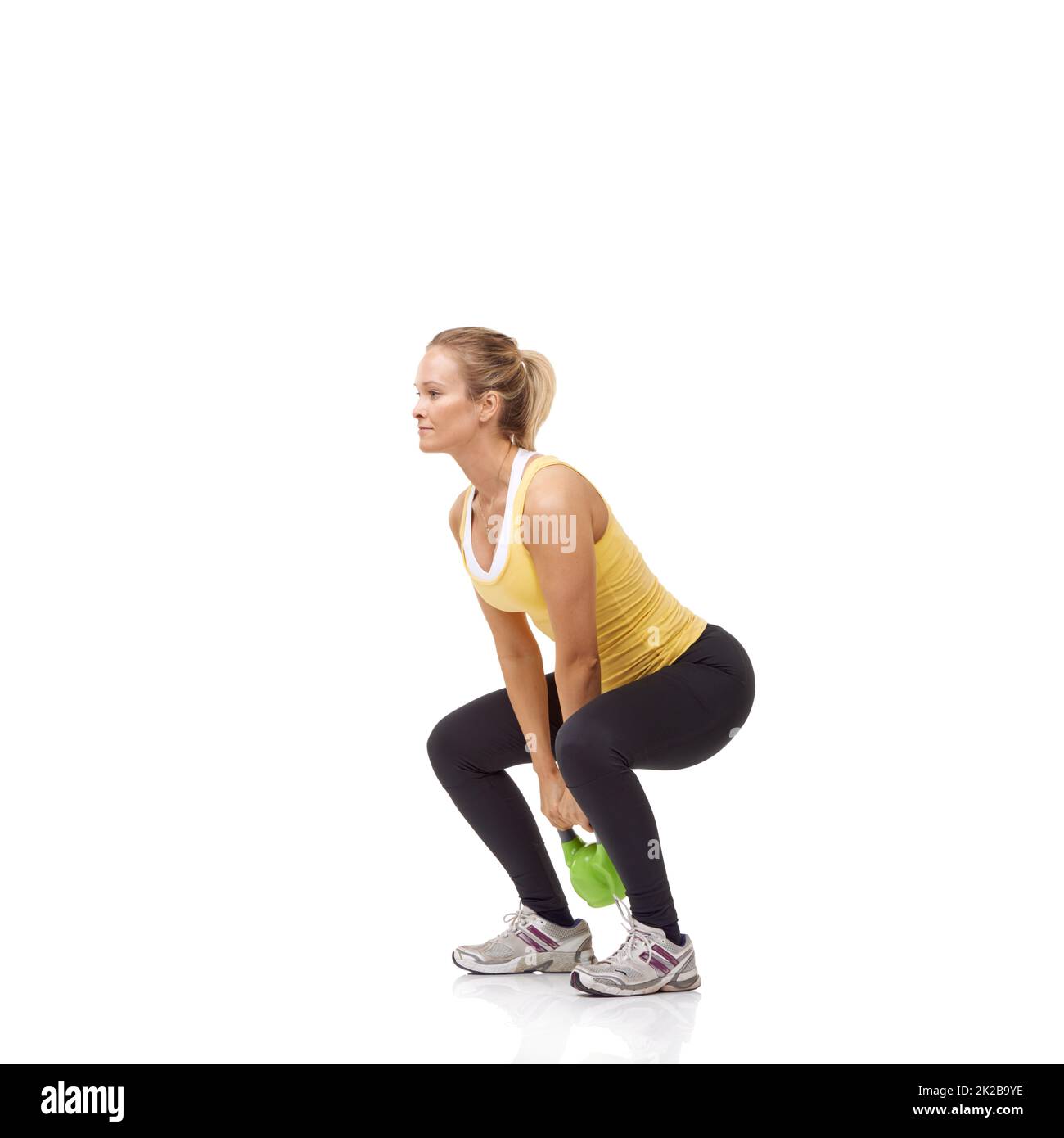 Getting ready to swing her kettlebell. A beautiful blonde woman performing a two-handed kettlebell swing. Stock Photo