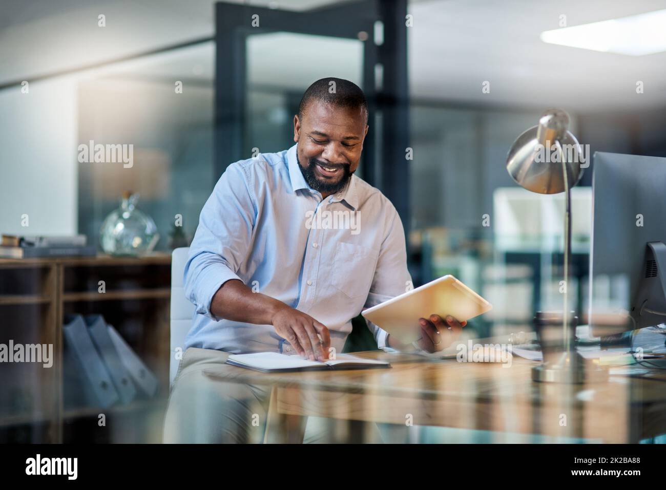 Another goal reached during tonights shift. Cropped shot of a handsome mature businessman sitting alone in his office at night and using a tablet. Stock Photo
