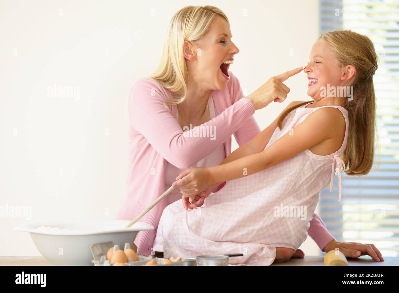Got you. A mother playfully putting flour on her daughters nose while baking together. Stock Photo