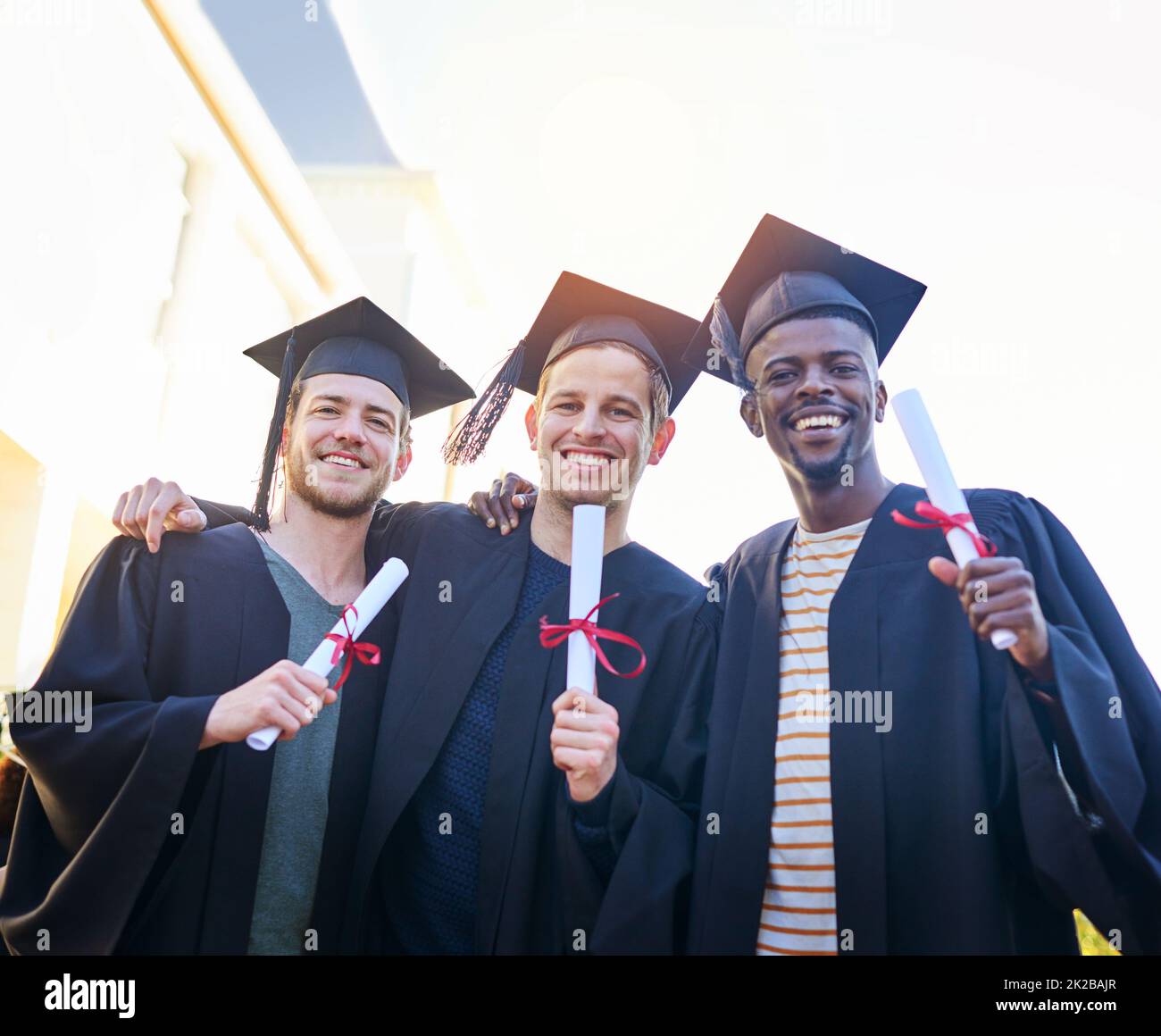 We worked hard to be holding this. Shot of students on graduation day from university. Stock Photo