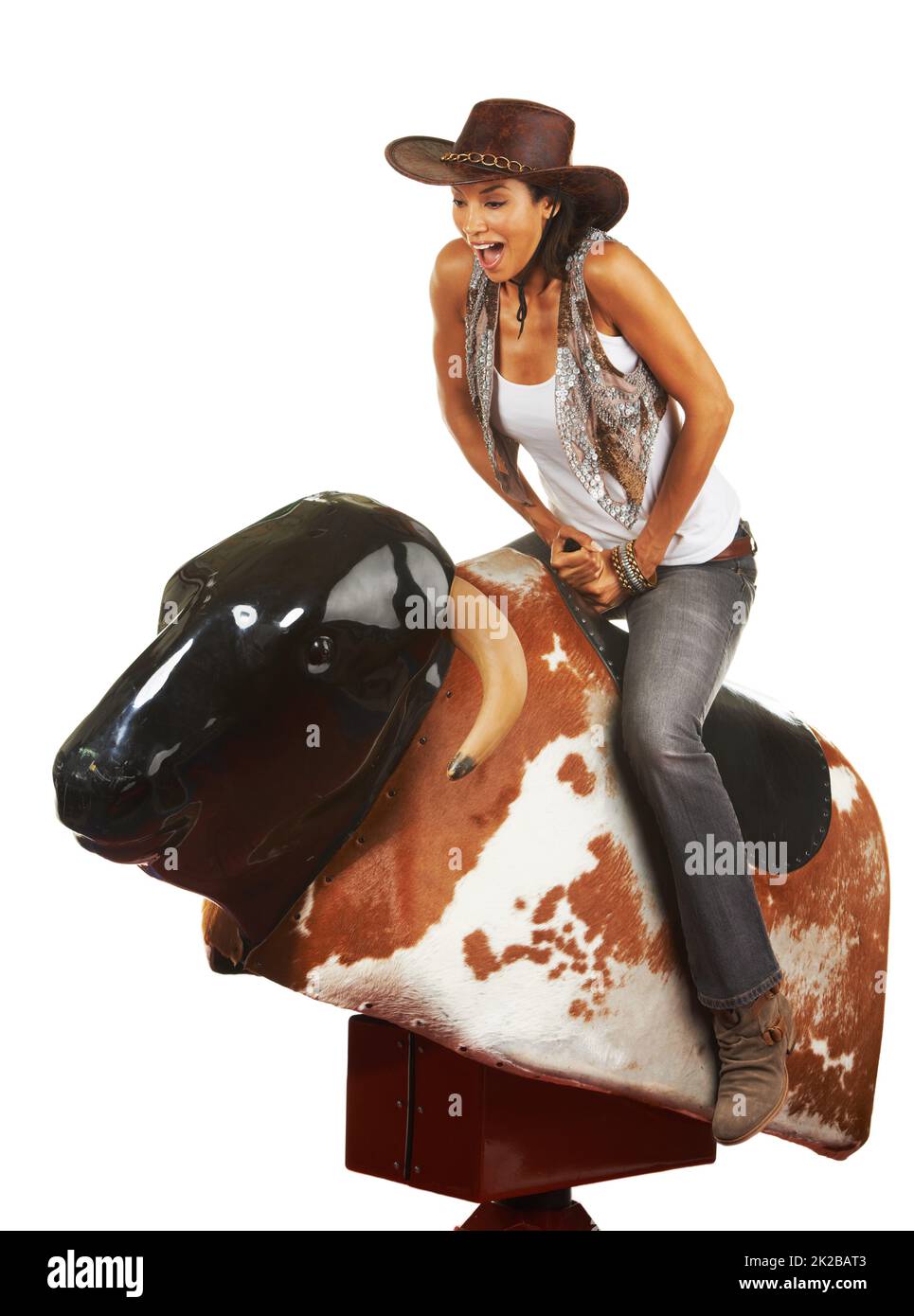 Woah. Studio shot of a beautiful young woman riding a mechanical bull against a white background. Stock Photo