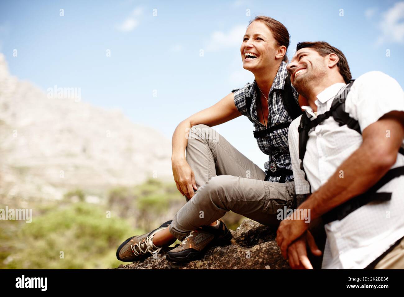 Romance out in nature. Two hikers laughing and smiling while enjoying a mountain top view. Stock Photo
