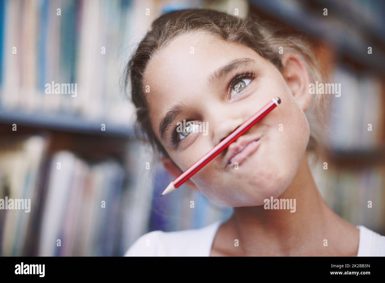 Class clown. A cute young girl balancing her pencil on her lips and pulling a face. Stock Photo