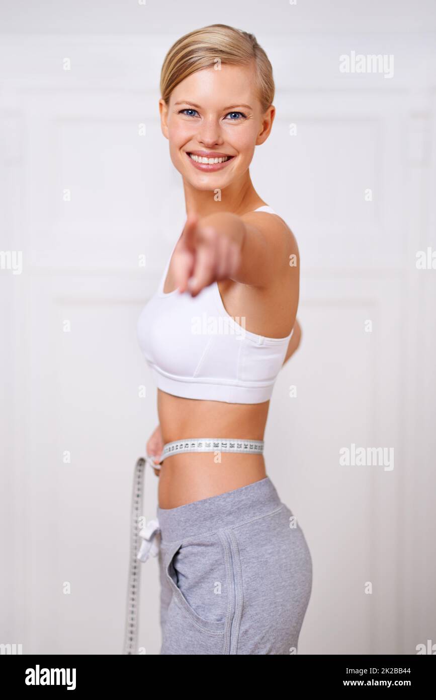 Ive reached my goal weight and so can you. A portrait of a beautiful young woman measuring her waist and pointing. Stock Photo