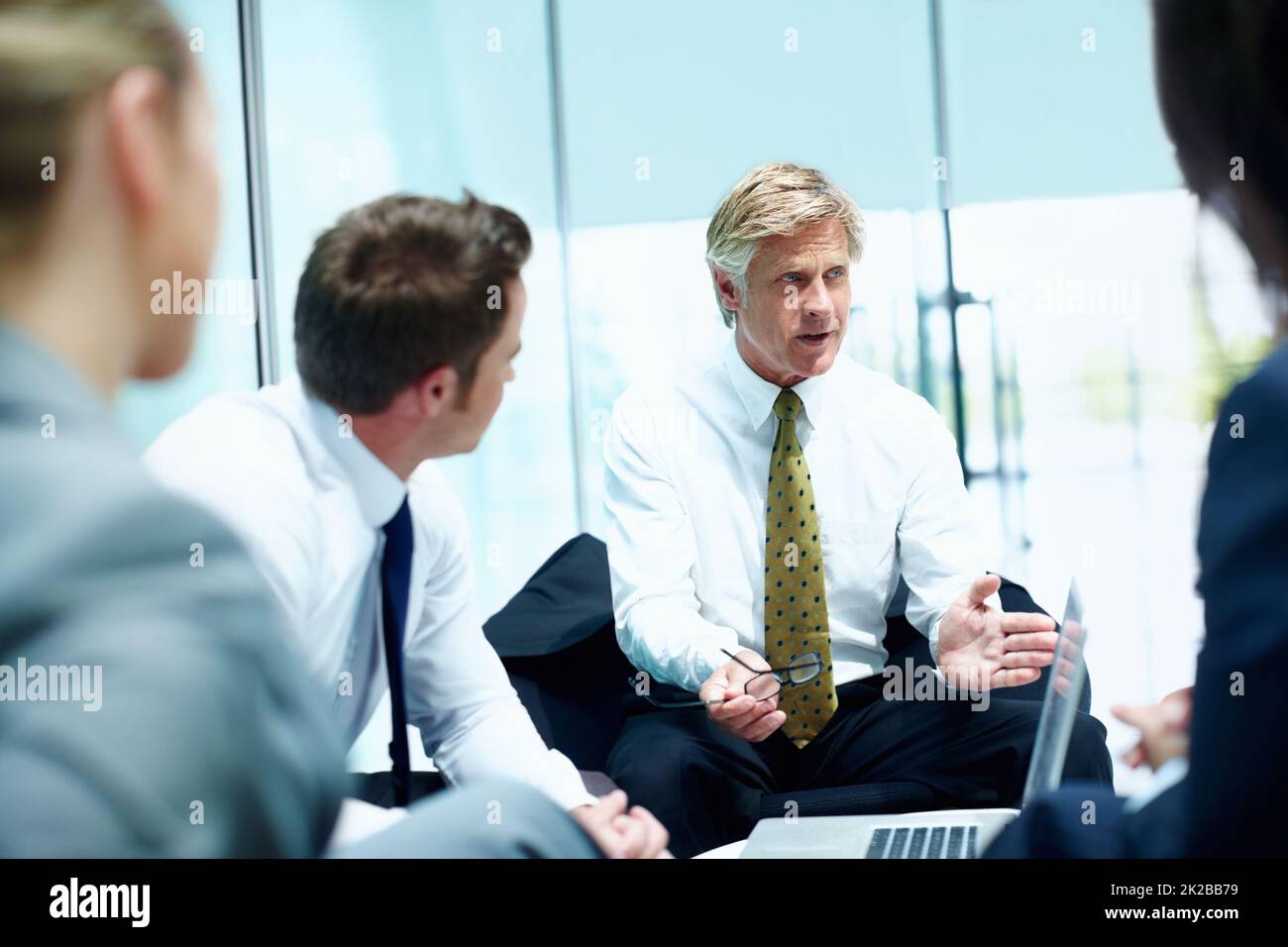 Business man conversing in meeting. Mature business man conversing with his executives during meeting. Stock Photo