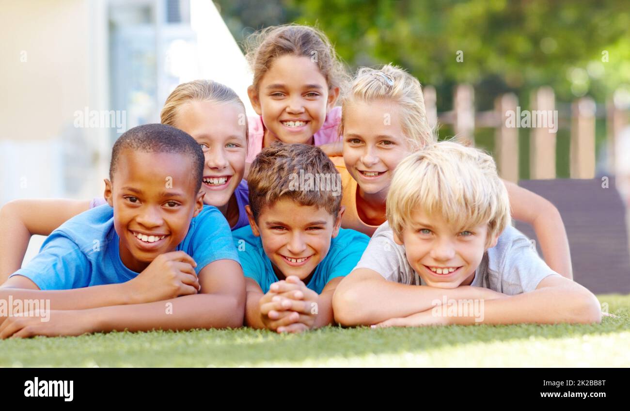 Healthy lifestyles make happy kids. A group of cute primary school kids lying down in pyramid formation outside. Stock Photo