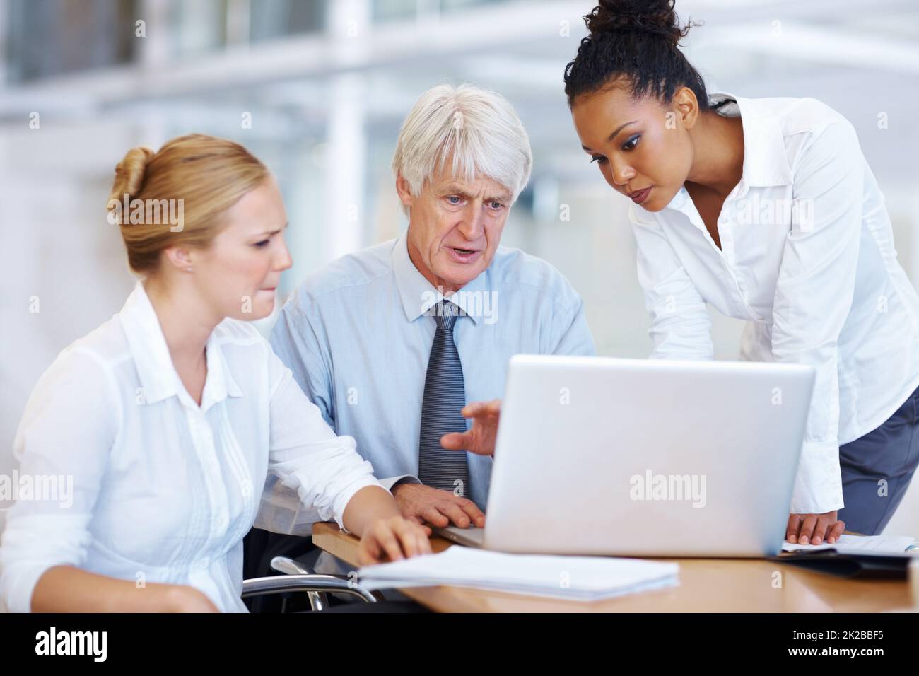 Associates using laptop. Portrait of multi ethnic associates working on laptop together at office. Stock Photo