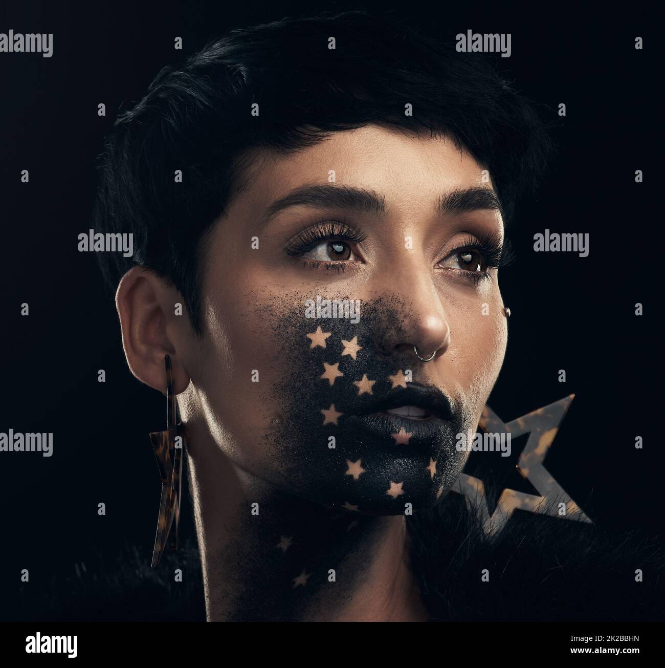 A star in the making. Studio shot of a young woman posing with paint on her face on a black background. Stock Photo