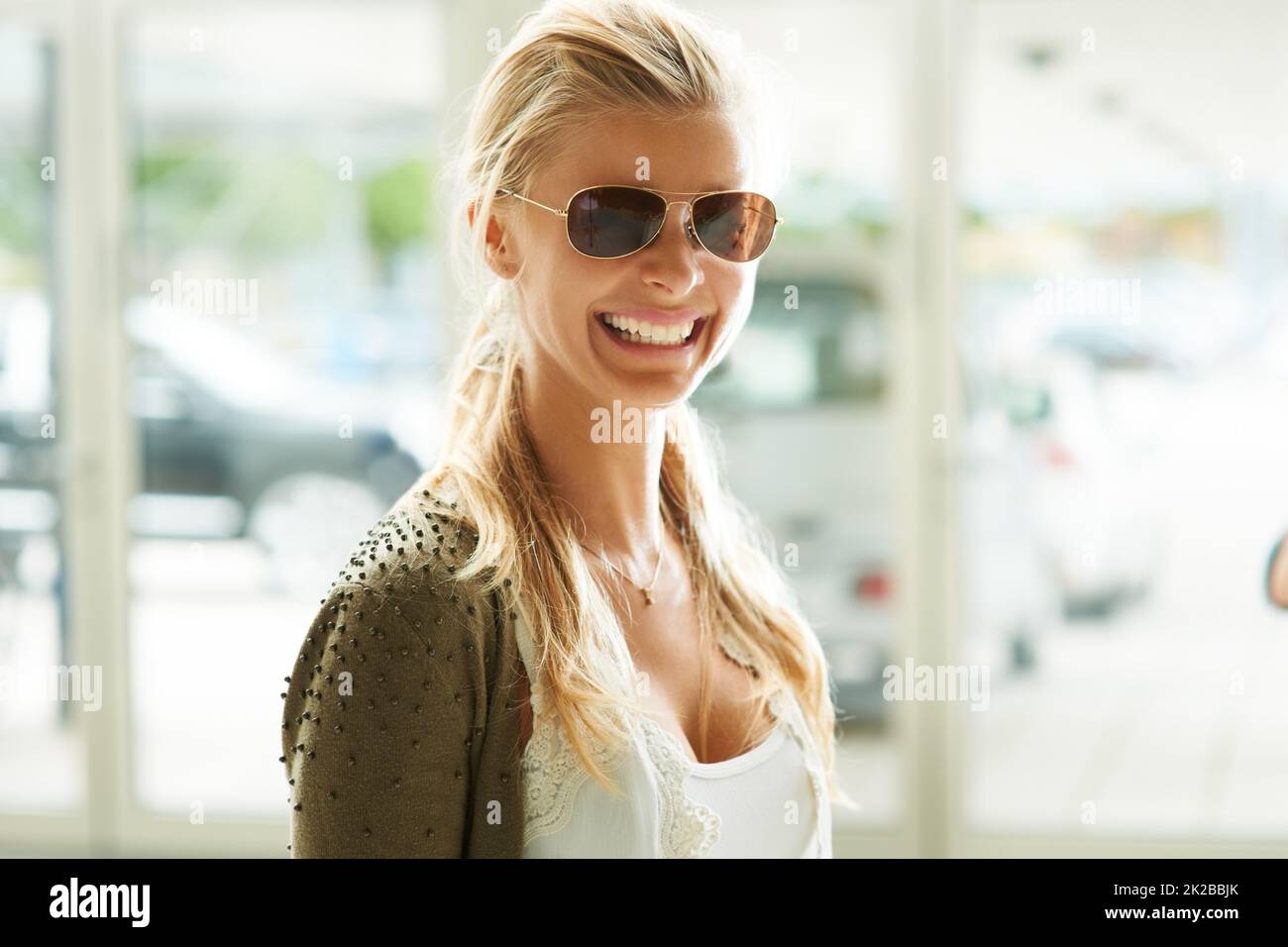Arriving in style. Pretty young woman wearing fashionable sunglasses and smiling. Stock Photo