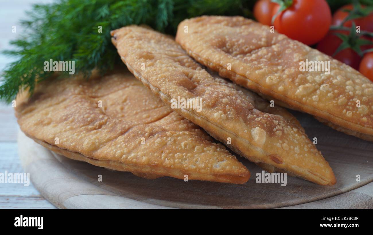 Cheburek with meat and cherry tomatoes. Traditional Romania, Ukrainian, Russian and Tatar food National east meal. Meat pie  with beef, veal or lamb Stock Photo