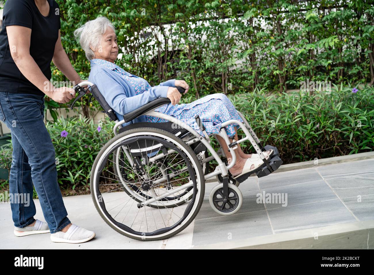 Caregiver help and care Asian senior or elderly old lady woman patient sitting on wheelchair at nursing hospital ward, healthy strong medical concept Stock Photo