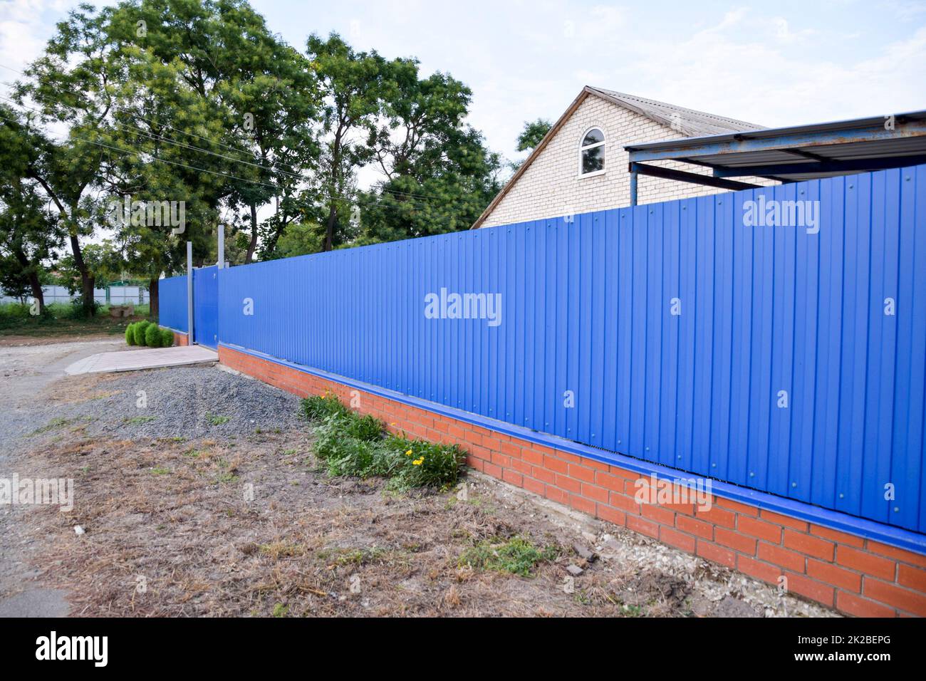 Fence and gate from sheets of blue corrugated metal. Stock Photo