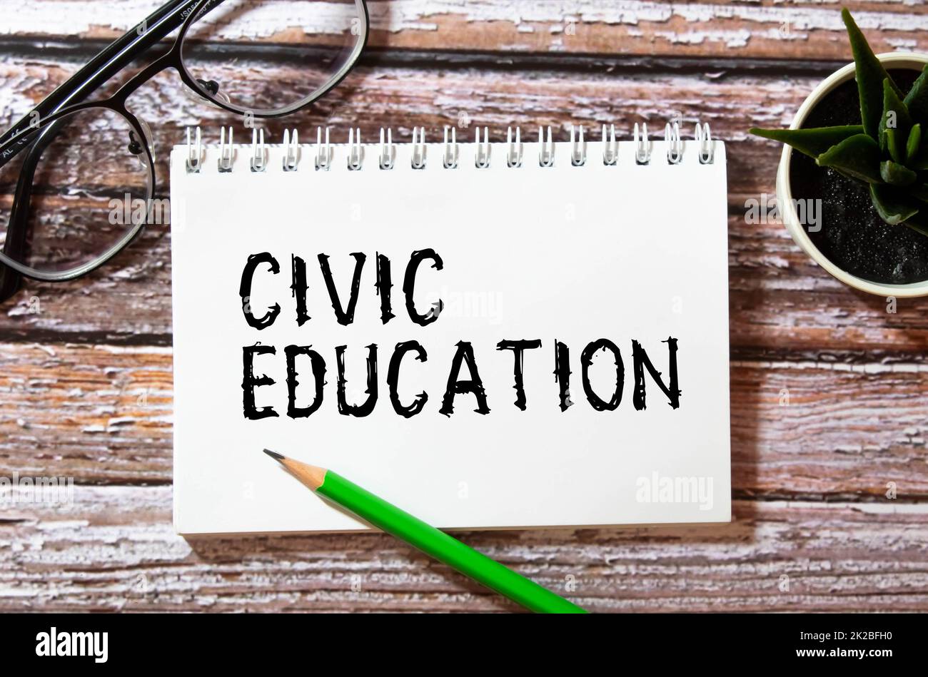 The word CIVIC EDUCATION is written in a white notepad near a white cup of coffee on a light background. Stock Photo