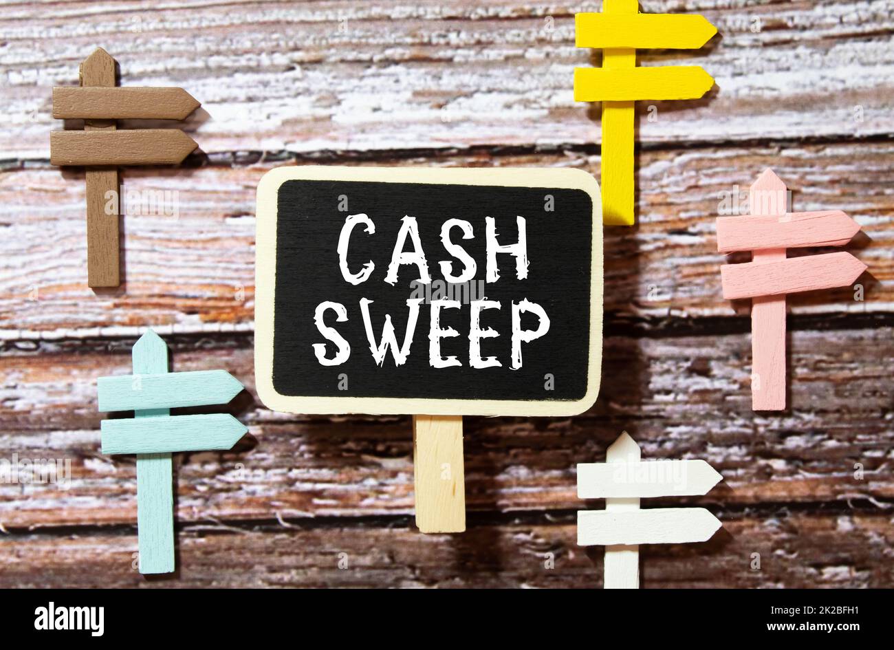 On a white surface are twisted dollars, a notebook and a cardboard sign with the inscription - Cash sweep. Stock Photo