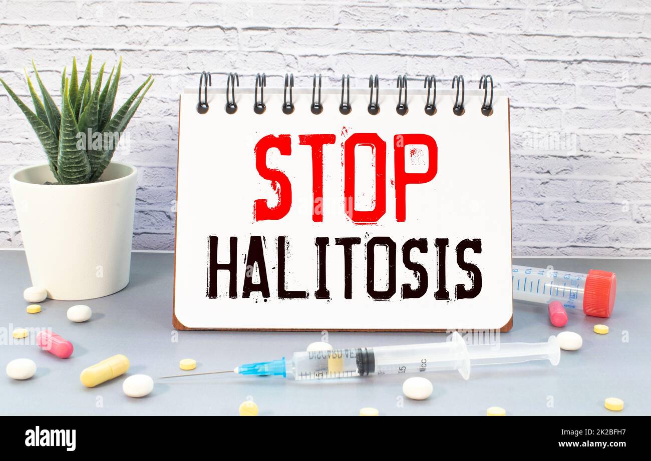 On a blue background ampoule with medicines and a notebook with the text STOP HALITOSIS. Medical concept Stock Photo