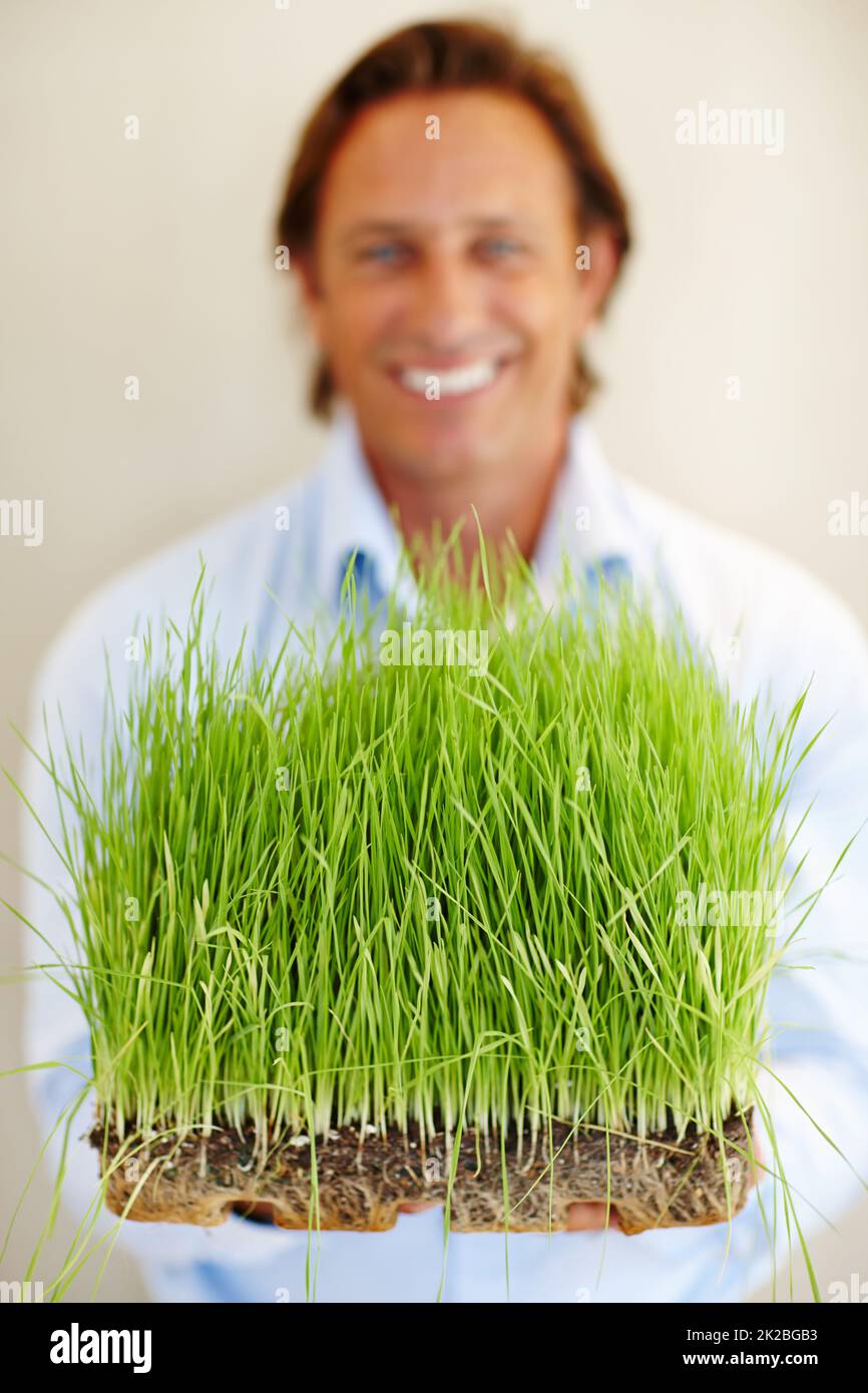 Everything fresh and green. Shot of a man holding out a patch of grass. Stock Photo
