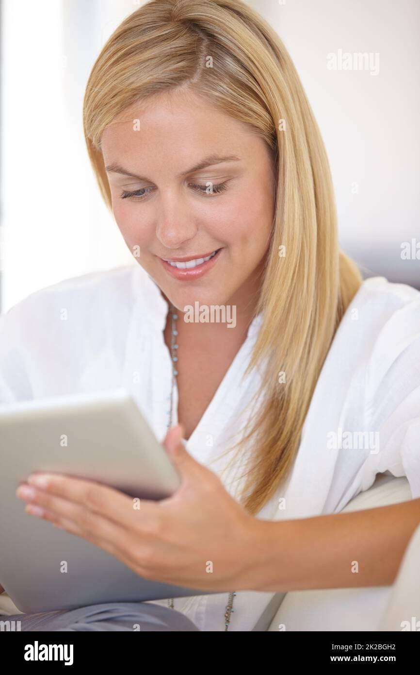 Checking her work schedule. A beautiful young blonde woman working on her digital touchpad. Stock Photo
