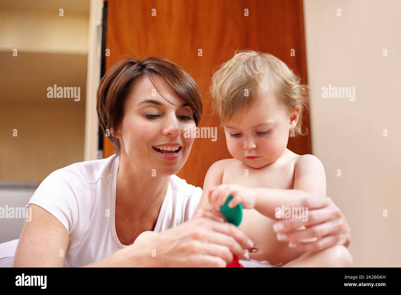 Youre such a big girl, holding it by yourself. A mother showing her baby girl a colorful spoon. Stock Photo