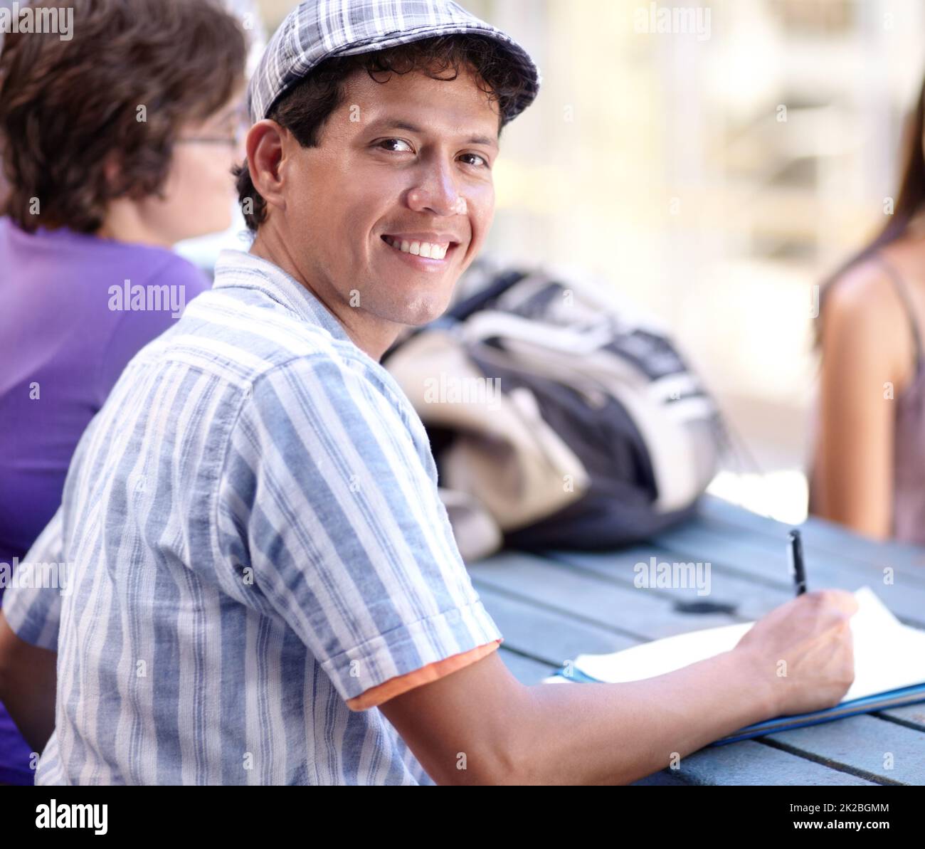 He uses breaktime for extra studies. A young ethnic man writing down some notes during break. Stock Photo