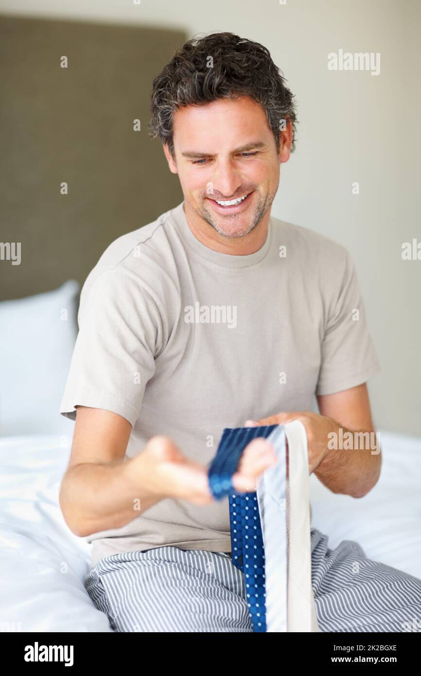 Man choosing a tie. Smiling man trying to decide which tie to wear. Stock Photo