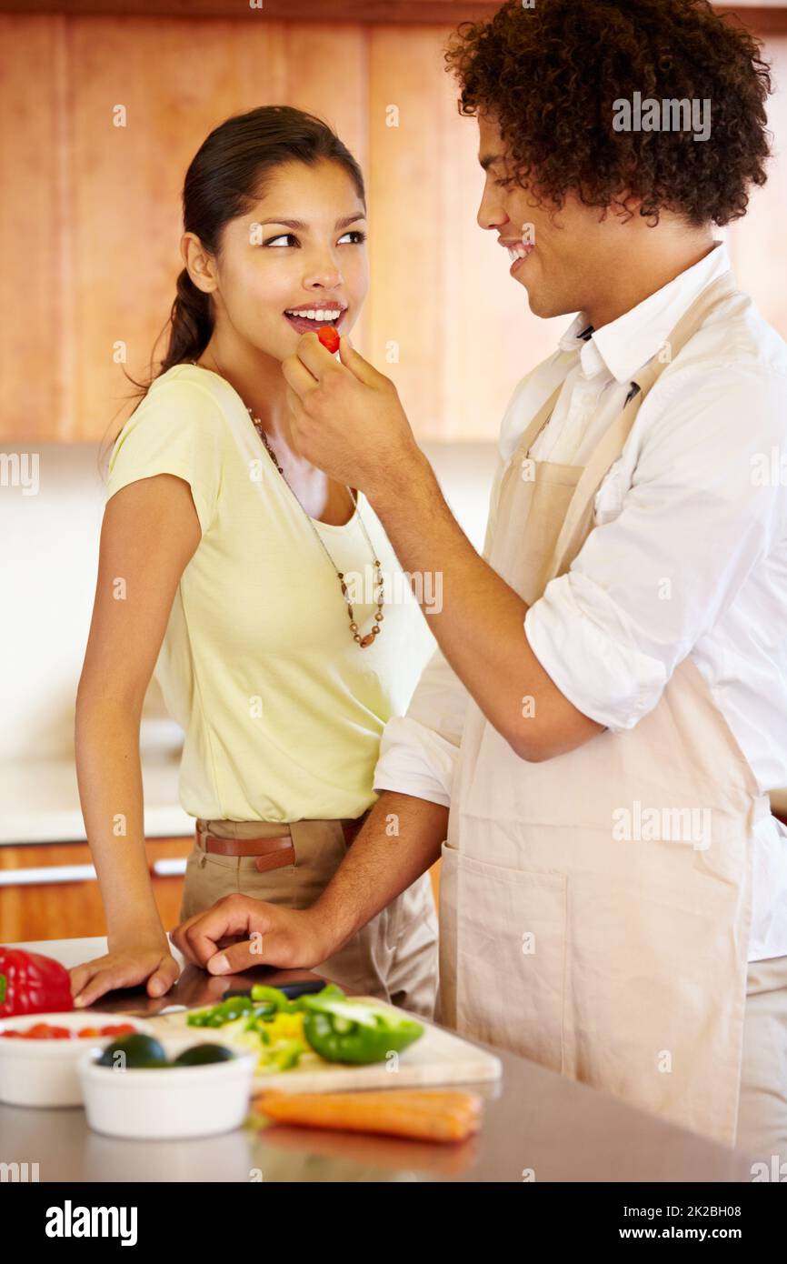 Nom nom nom. A young man feeding his girlfriend a bite of pepper. Stock Photo