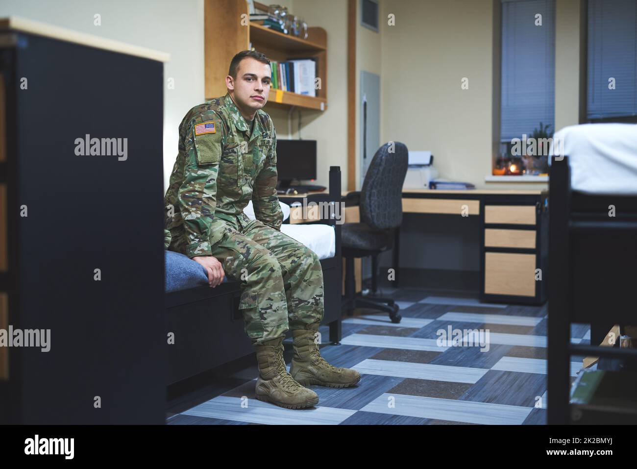Some call it a dorm, I call it home. Shot of a young soldier sitting on his bed in the dorms of a military academy. Stock Photo
