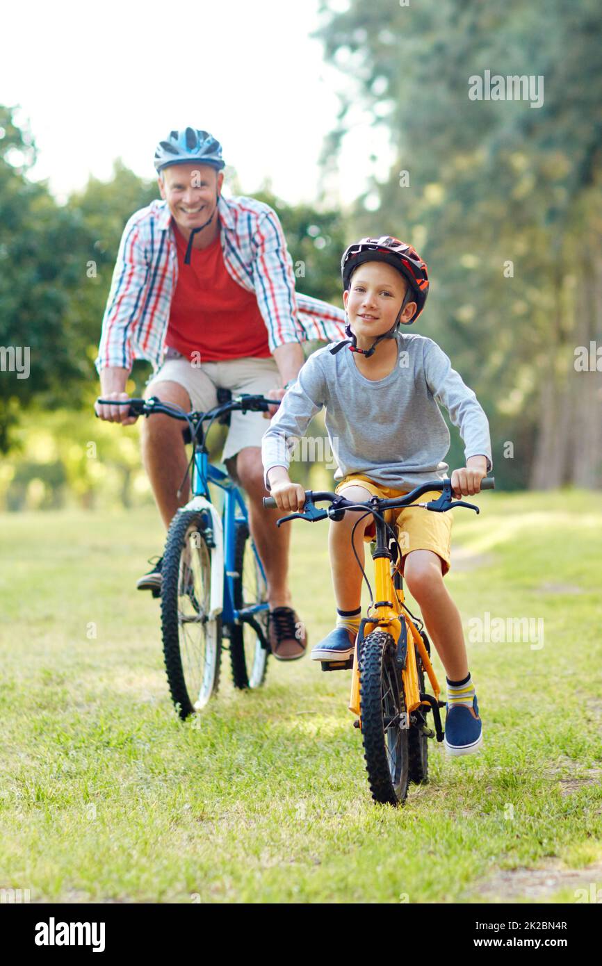 Enjoying a day out with dad. Shot of a father and son riding bicycles in a park. Stock Photo