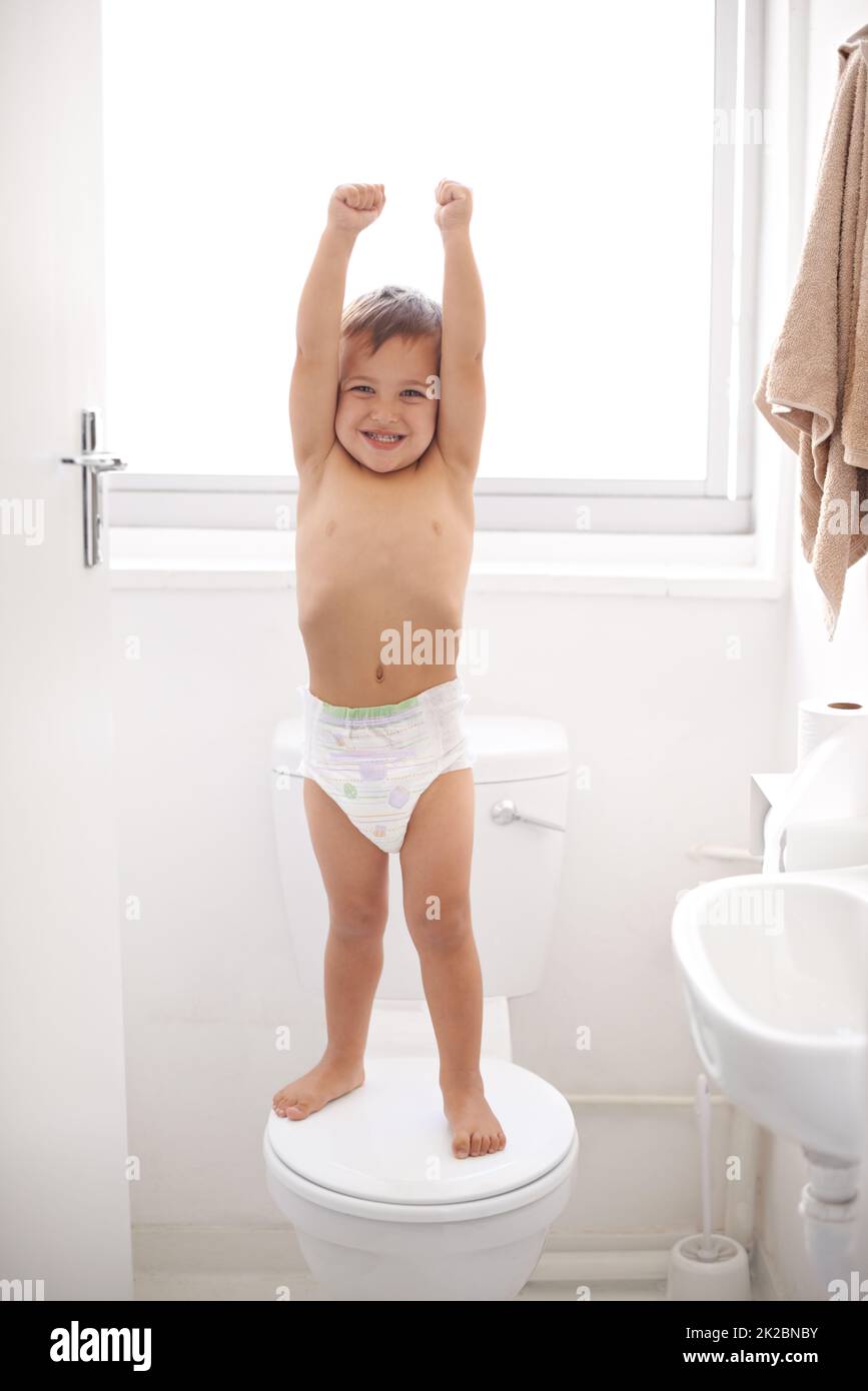 Im a big kid now. Shot of a happy young boy in a diaper standing on a toilet seat. Stock Photo