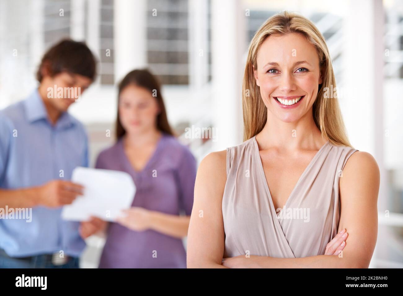 Im taking my team to the top. Shot of a leader smiling at the camera with colleagues blurred in the background. Stock Photo
