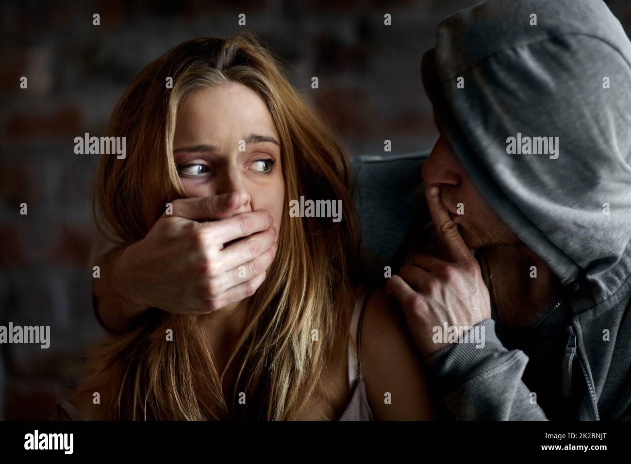 Held captive. Abused young woman being silenced by her abuser. Stock Photo